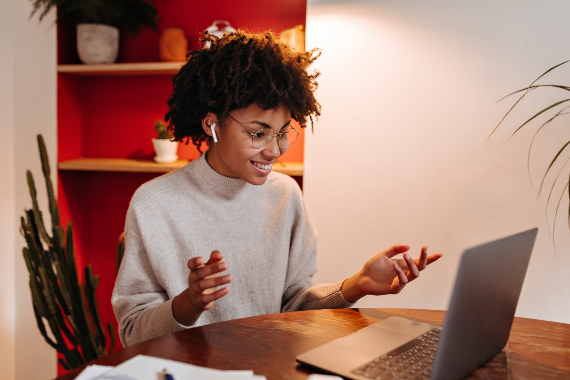 Charming lady with smile looks into laptop, communicates via video link in wireless headphones