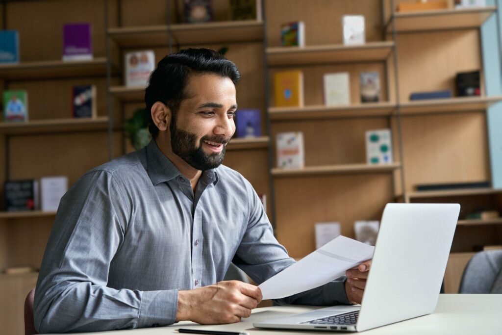 Smiling indian business man holding cv document having virtual job interview.