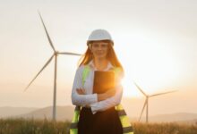 Woman in helmet working with tablet at renewable energy farm
