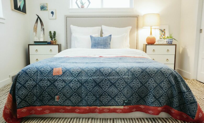 A bedroom in an apartment with a bed and a patterned bed cover.