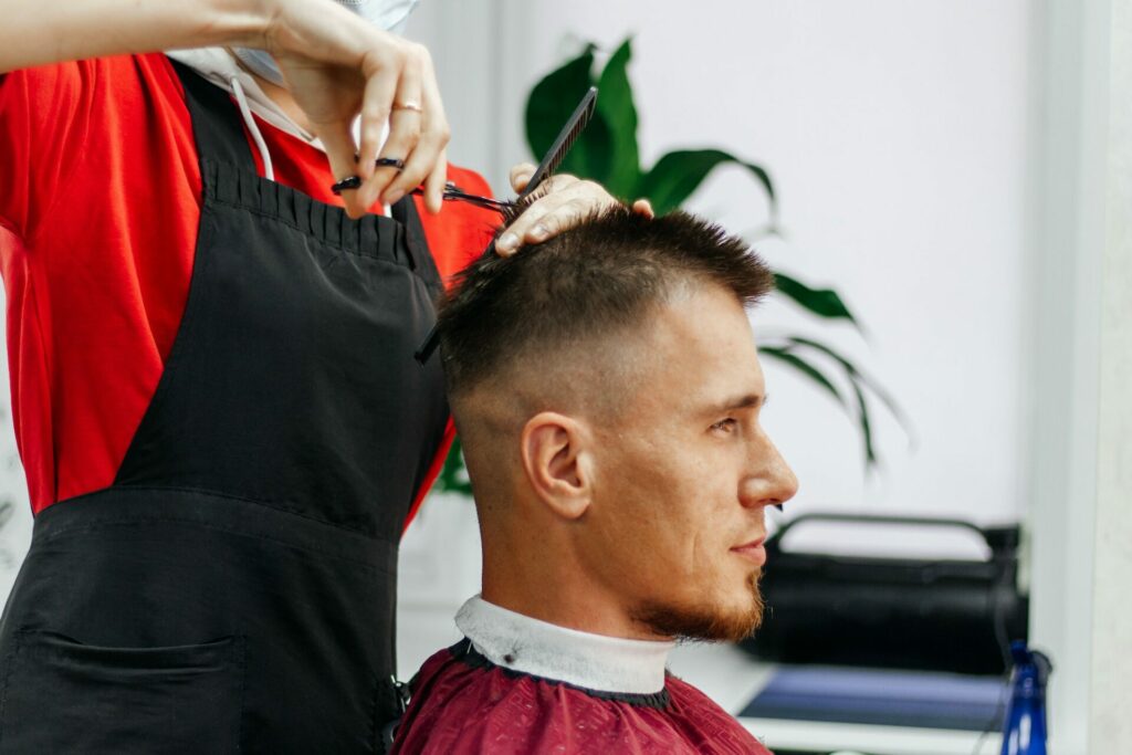 European man is cut by a barber. Men's hair cutting with scissors in the salon