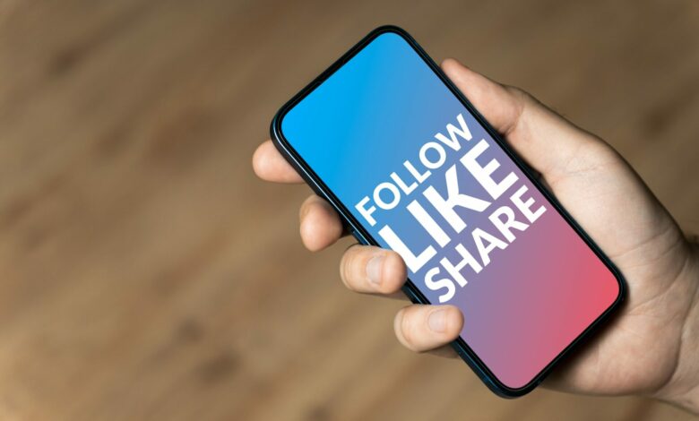 Follow Like Share - hand holding a phone