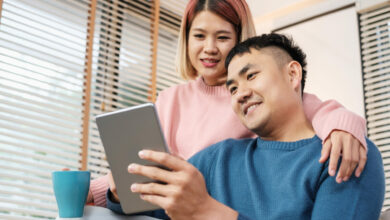 Asian couple watching video live on tablet on sofa in living room