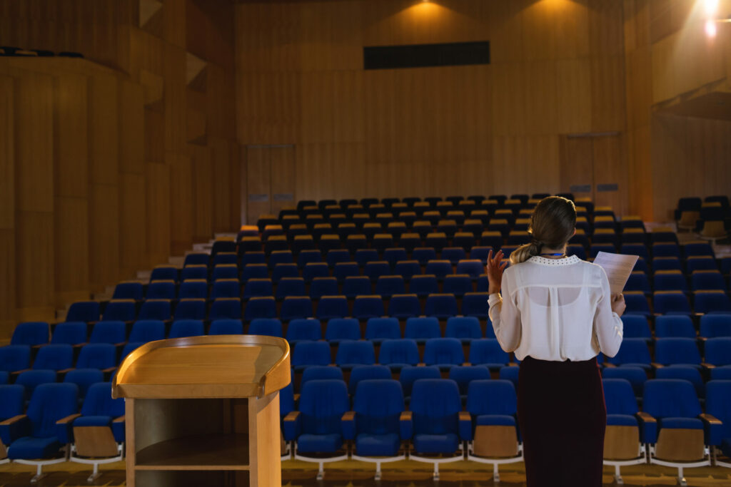 Businesswoman practicing and learning script while standing in the auditorium