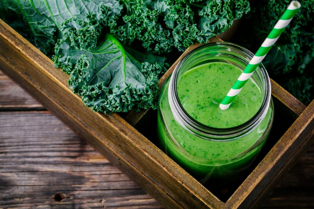 Healthy green smoothie with kale in mason jar on wooden background