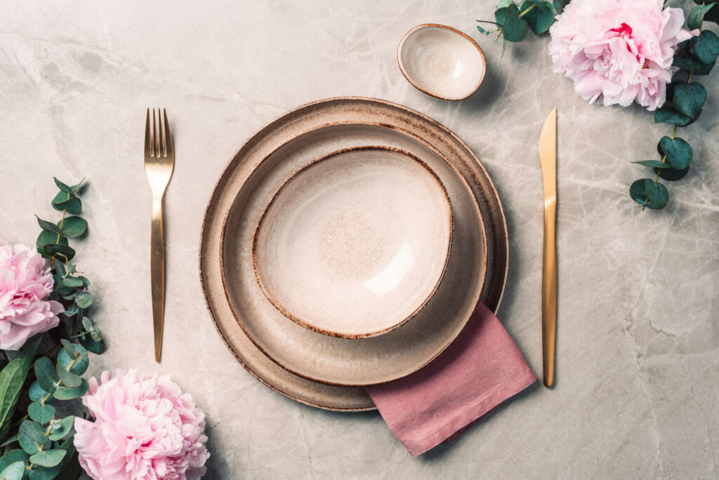 Tableware, flowers for serving a festive table, dinner. Stoneware plates, golden cutlery, eucalyptus