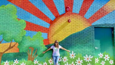 Beautiful woman raising her arms with a Bright and colorful painted background wall mural!