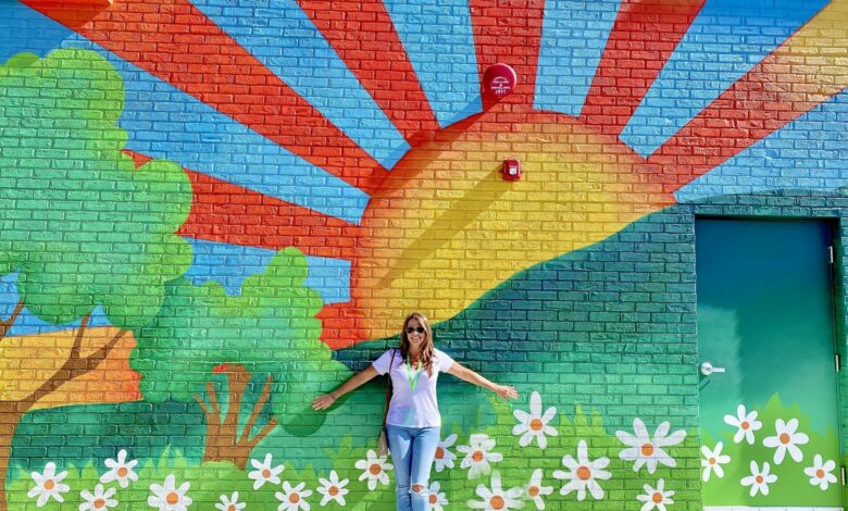 Beautiful woman raising her arms with a Bright and colorful painted background wall mural!