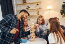 Wooden tower game on the table. Group of friends have party indoors together