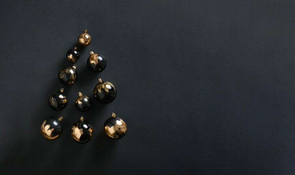 Banner with Christmas Tree made of golden and black balls on black.