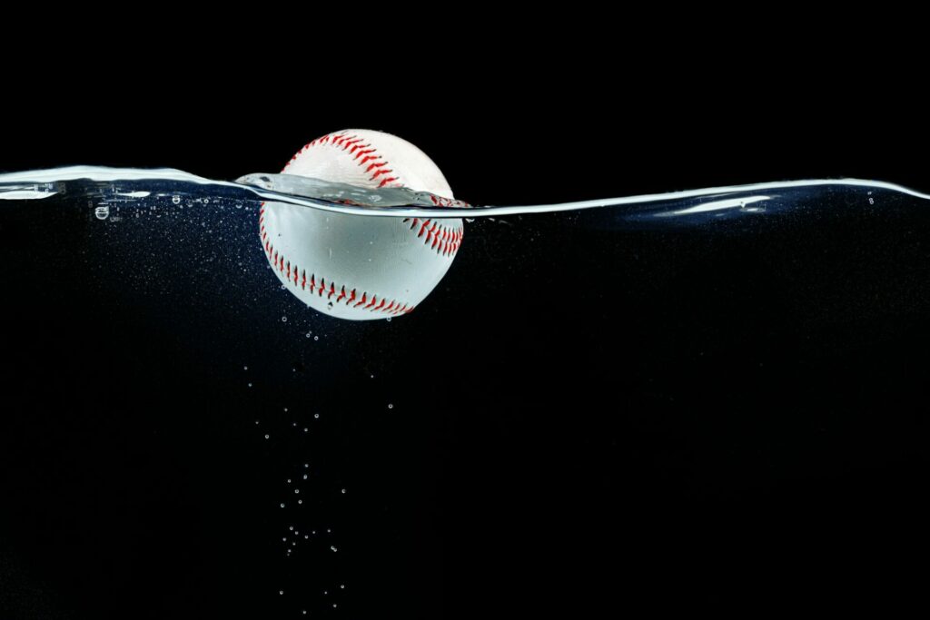 Baseball ball floating in the water against black background