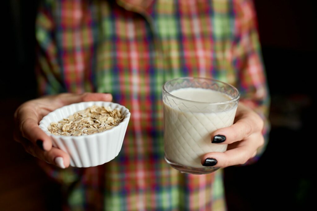 Female hands with glasse of vegan oat milk, Alternative types of non-dairy milks