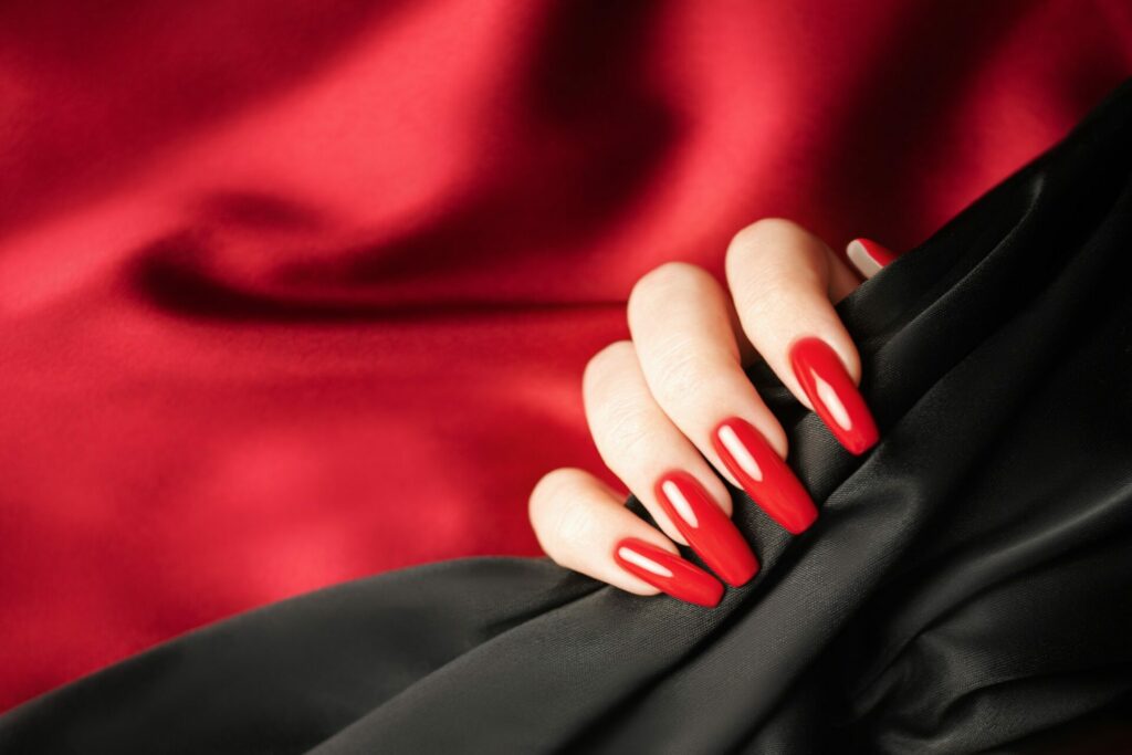 Hands of a young girl with red and black manicure on nails