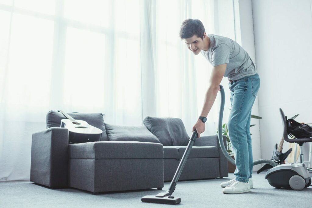 teenager vacuuming floor in living room with vacuum cleaner