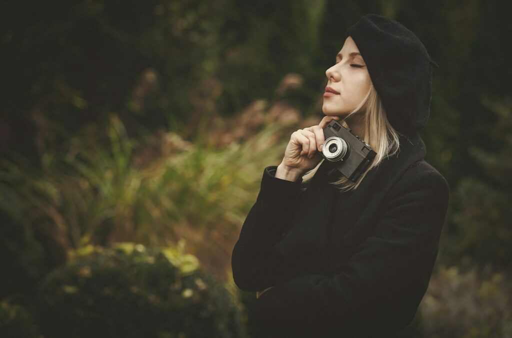 woman in black cloak and hat with vintage camera in outdoor