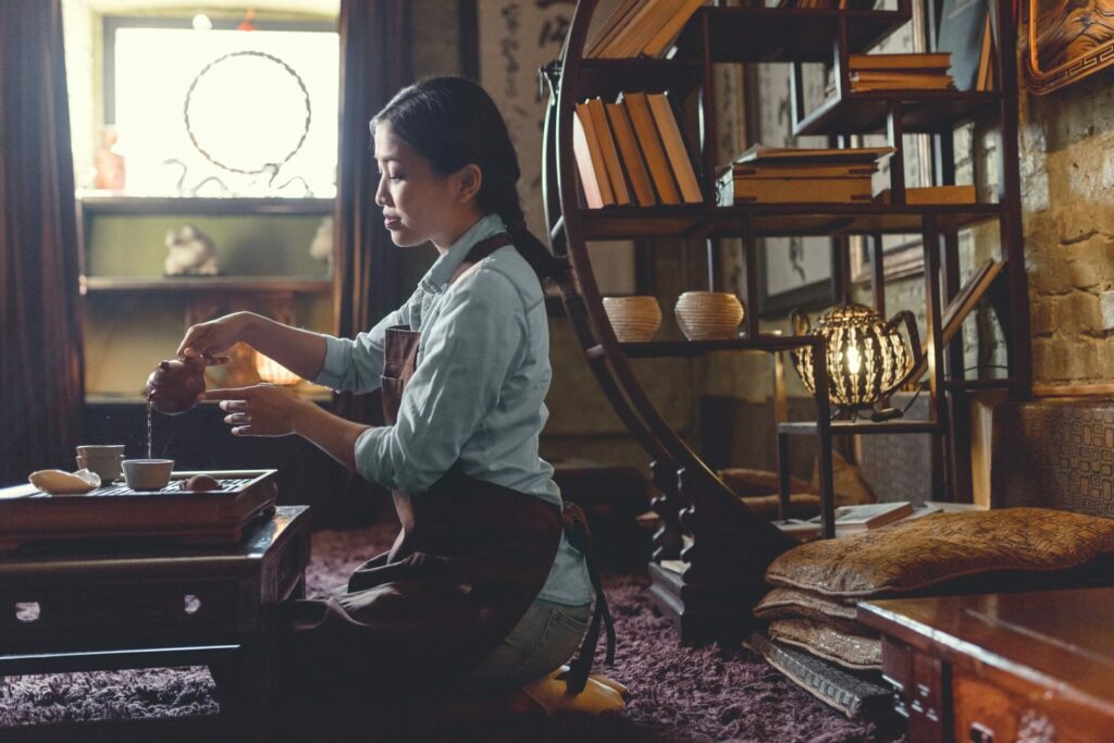 Young woman pouring tea in room