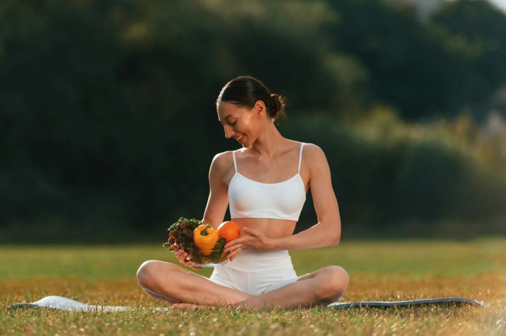 Holding vegetables. Young caucasian woman with slim rectangle body shape is in the fitness clothes outdoors