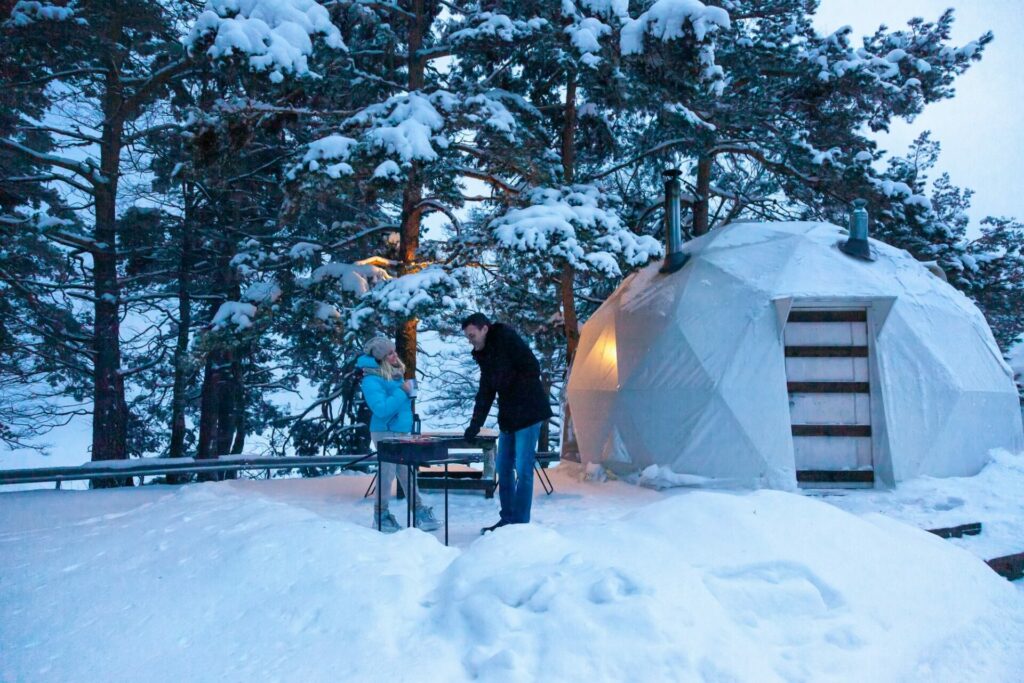 Outdoor recreation in glamping dome tent in snowy winter.