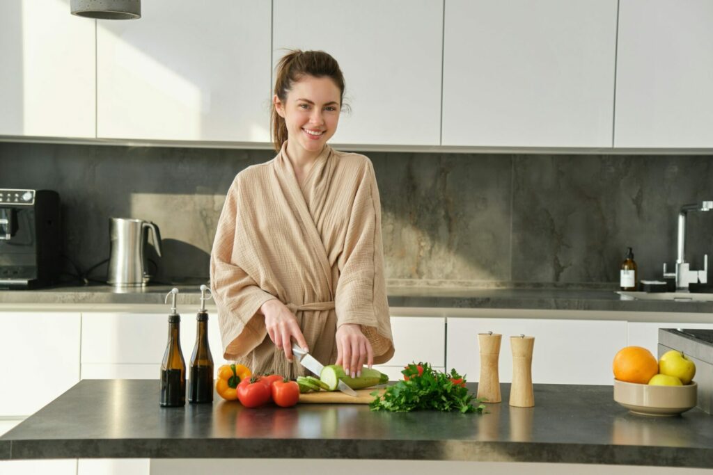 Portrait of good-looking woman cooking salad in the kitchen, chopping vegetables and smiling