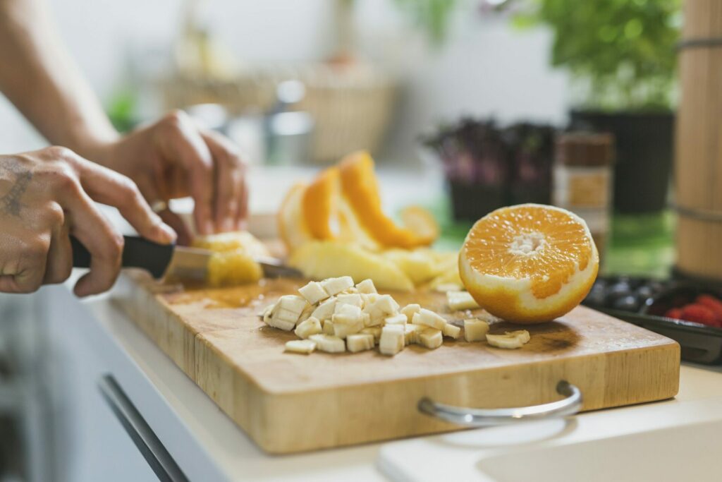 Woman preparing healthy meal and cutting fruits on chopping board