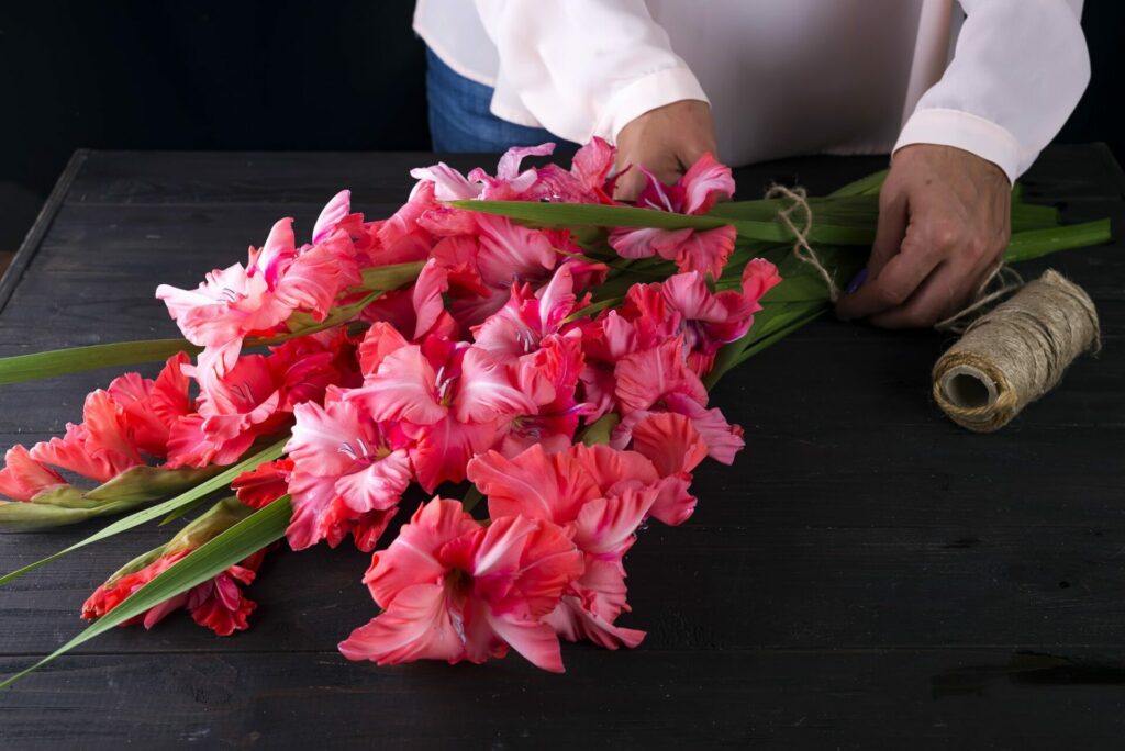 women's hands create a bouquet of flowers of gladiolus