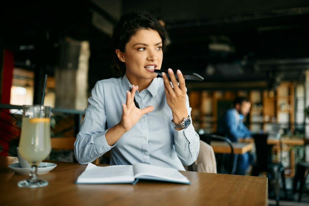 Young businesswoman recording voicemail on android while working in a cafe.