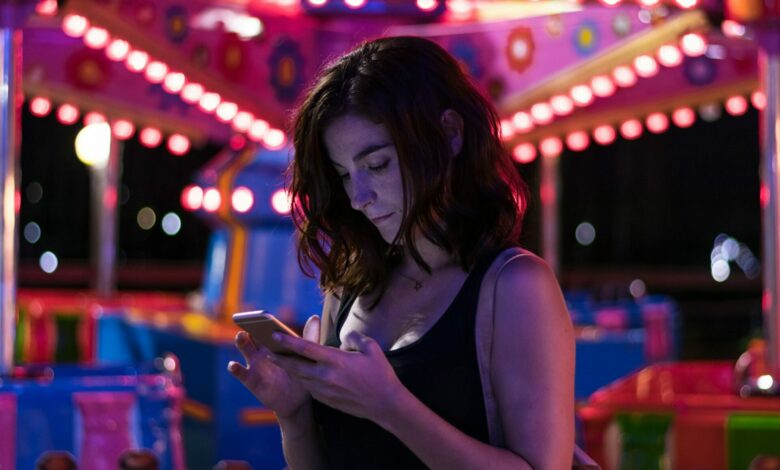 Young woman is checking her smartphone voicemail in a fair