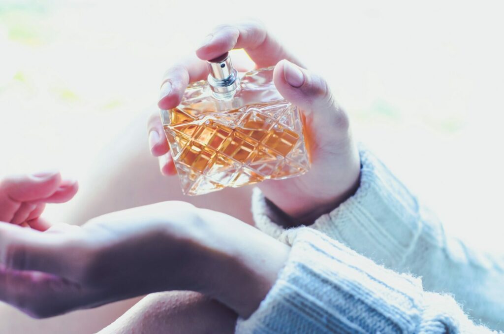 Young woman sprinkles luxury perfume on her wrist. Perfume in a woman's hand