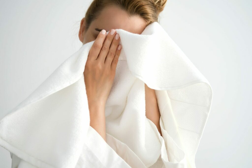 The girl wipes her combination skin face with a terry towel.