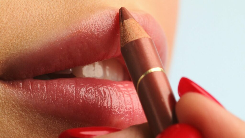 Visagiste making make up applying lipstick on a lip