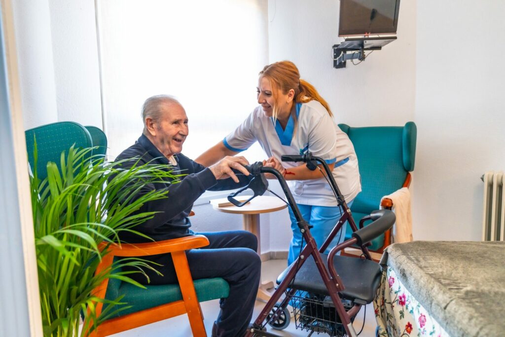 Nurse assisting a man to stand up in the geriatrics